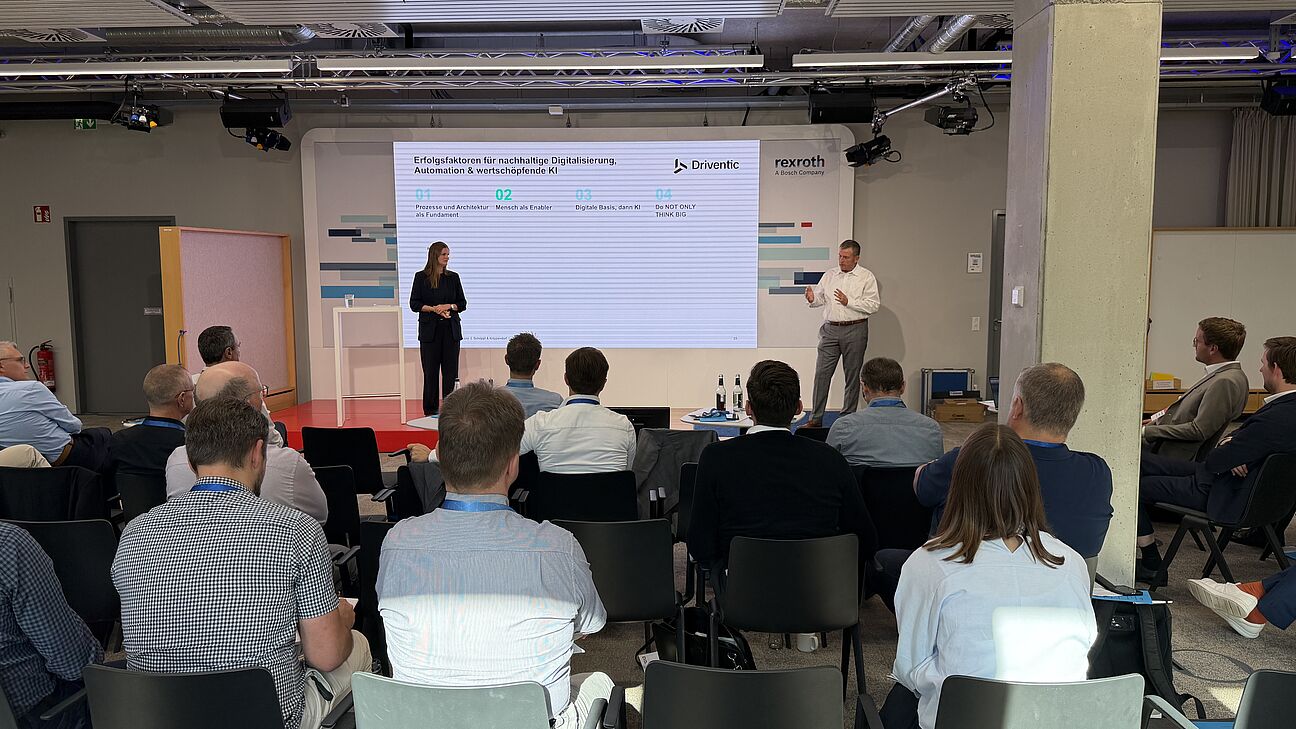 Automation Next Conference 2026 - Pia Schöppl & Steffen Krippendorf stehen auf der Bühne und spricht zum Publikum