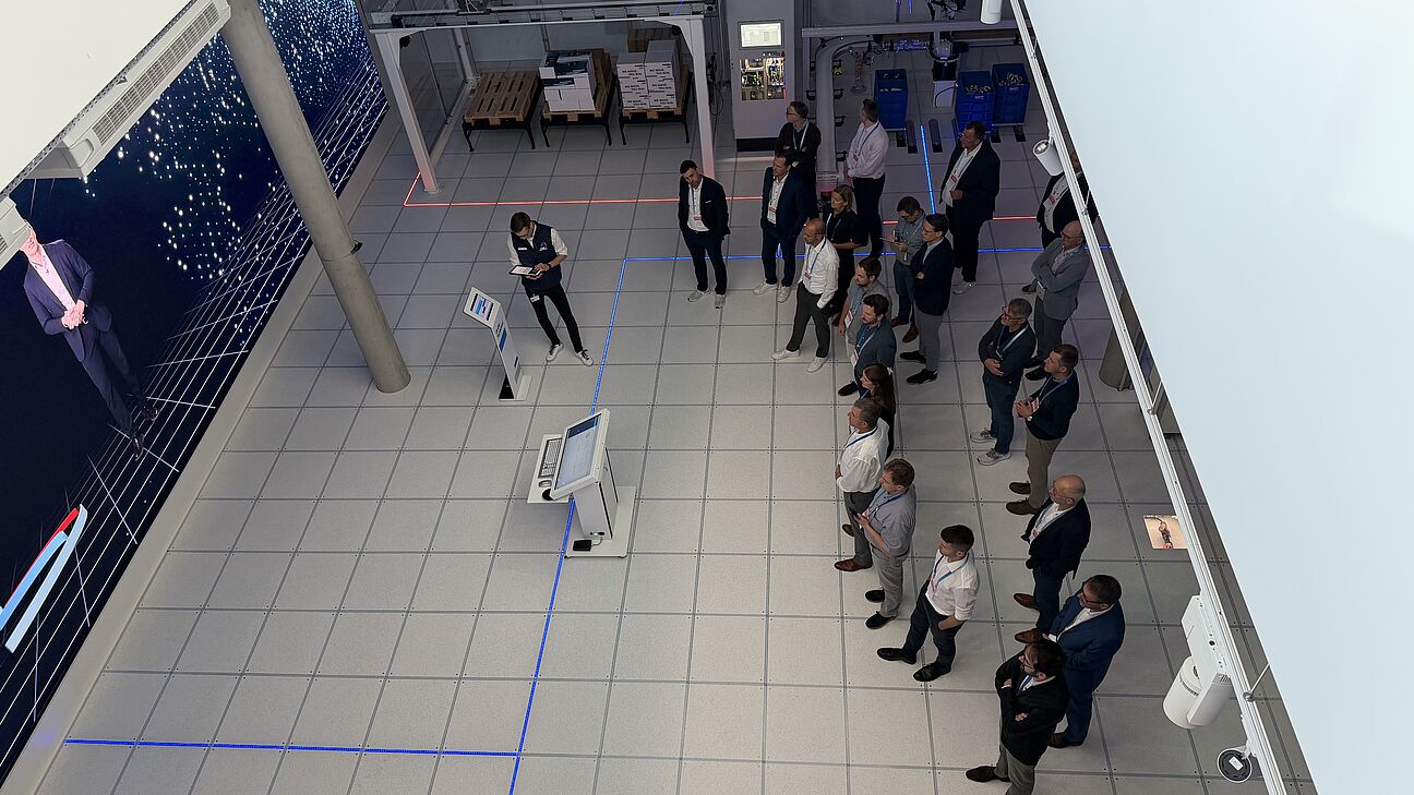 Automation Next Conference 2026 - ein Bild von oben. Die Teilnehmer stehen bei der Werksfürhung und schauen alle in die gleiche Richtung