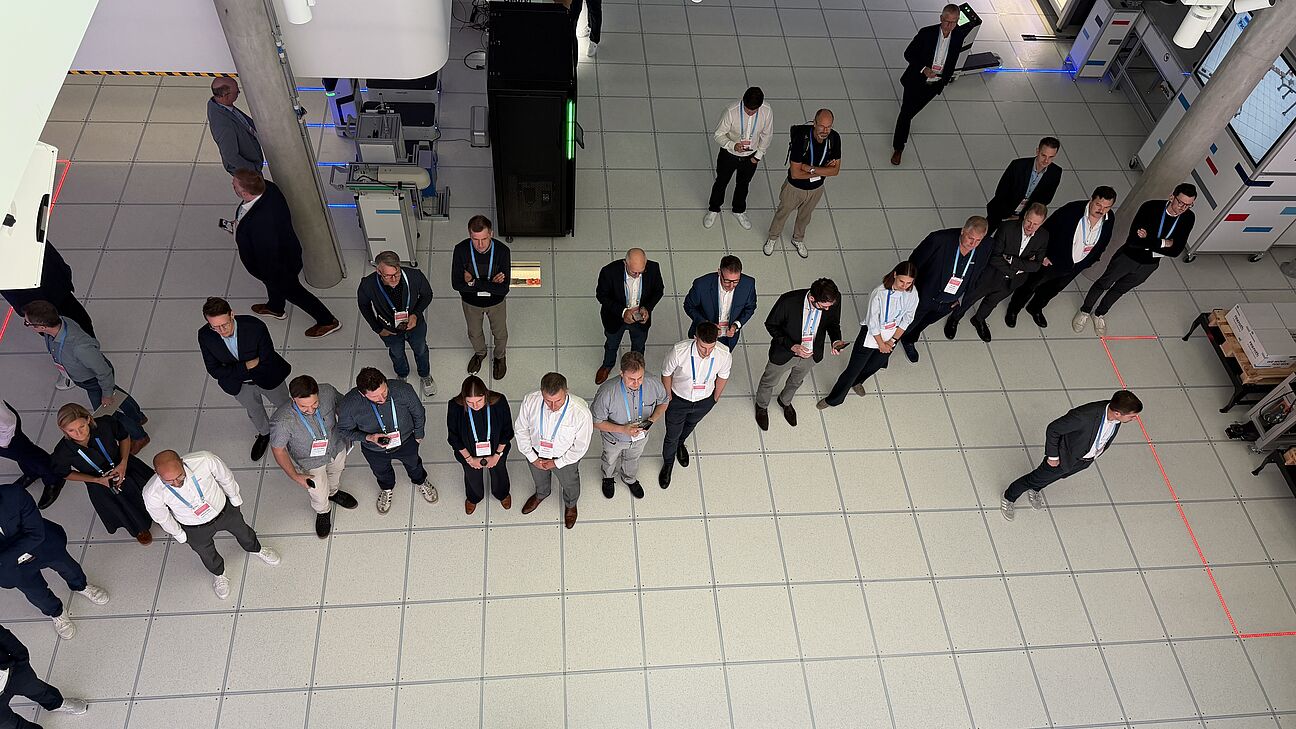 Automation Next Conference 2026 - ein Bild von oben. Die Teilnehmer stehen bei der Werksfürhung und schauen alle in die gleiche Richtung